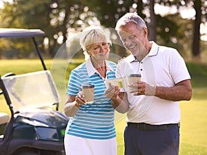 Senior Couple With Buggy On Golf Course Marking Score Card Together