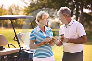 Senior Couple With Buggy On Golf Course Marking Score Card Together