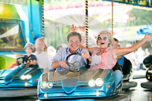 Senior couple in the bumper car at the fun fair