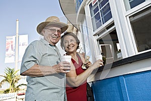 Senior Couple Buying Drinks At Food Stand