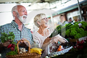 Senior couple buying fresh vegetables and fruits at the local market