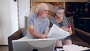 Senior couple calculating bills cost at home