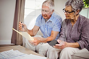 Senior couple calculating bills in living room