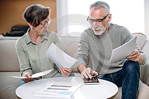Senior couple calculating utility bills, paying the loan or checking domestic finances
