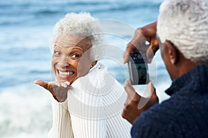 Senior Couple With Camera On Beach