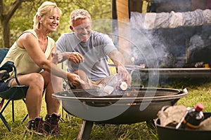 Senior Couple Camping In Countryside With RV Toasting Marshmallows Outdoors On Fire