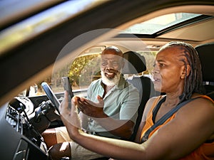 Senior Couple In Car Arguing About Directions On GPS Sat Nav On Mobile Phone On Day Trip Out 