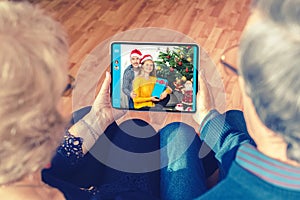 Senior couple celebrating Christmas chatting online from home with son and daughter