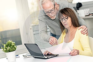 Senior couple checking financial document, light effect