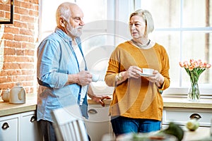 Senior couple with coffee near the window at home