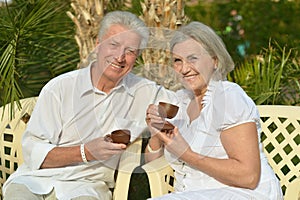 Senior couple with coffee in tropical garden