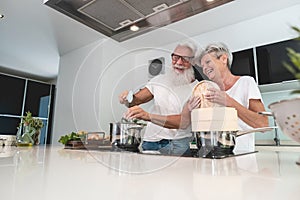 Senior couple cooking healthy meal at home in the kitchen - Elderly and joyful lifestyle - Focus on hands - food nutrition concept