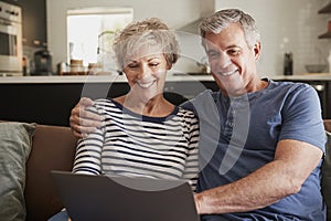 Senior couple on the couch at home using laptop, close up