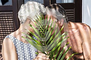 Senior couple cuddling behind a leaf