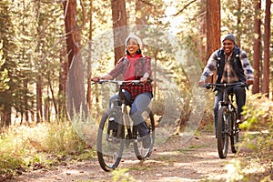 Senior Couple Cycling Through Fall Woodland