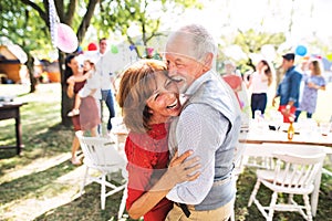 A senior couple dancing on a garden party outside in the backyard.