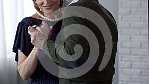 Senior couple dancing, man tenderly holding woman hand, special occasion