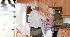Senior couple dancing together in kitchen