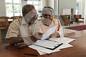 Senior couple discussing over invoices at home photo