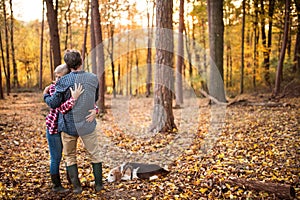 Senior couple with dog on a walk in an autumn forest.