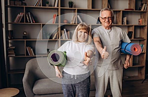 Senior couple is doing fitness training at home.Standing with fitness yoga carpets. Healthy lifestyle concept.