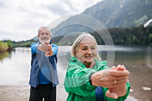 Senior couple doing outdoor yoga by the lake in the mountains.