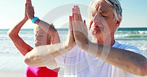 Senior couple doing yoga at beach