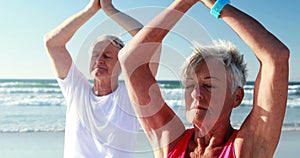 Senior couple doing yoga at beach