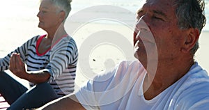 Senior couple doing yoga at beach