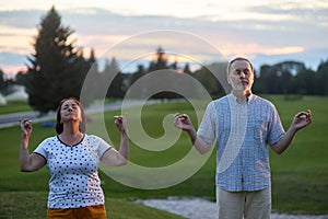 Senior couple doing yoga in the park.