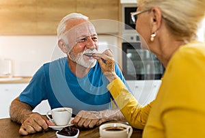 Senior couple drinking coffee and eating chocolate at home