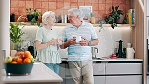 Senior couple, drinking coffee and happy communication in kitchen, bonding and relaxing together. Elderly people, tea