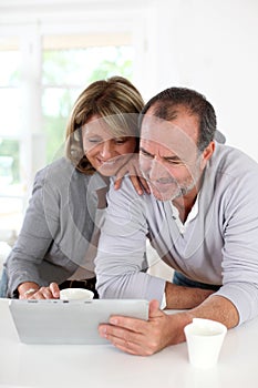 Senior couple drinking coffee and using tablet