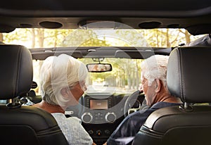 Senior Couple Drive Open Top Car On Countryside Road Trip