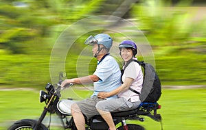 Senior couple driving motorcycle with dynamic background