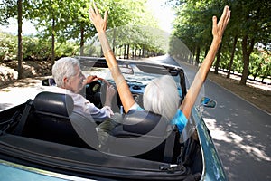 Senior couple driving in sports car