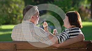 Senior couple eating an ice cream sitting on bench at park.