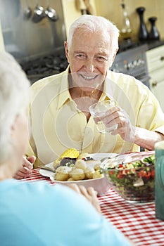Senior Couple Eating Meal Together In Kitchen