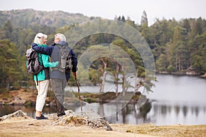 Senior couple embracing and admiring a view of lakes looking at each other, back view