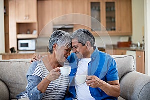 Senior couple embracing each other while having coffee in living room