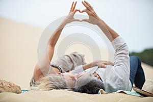 senior couple enjoying beach holiday laying on dune