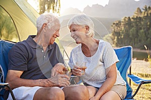 Senior Couple Enjoying Camping Vacation By Lake Making A Toast