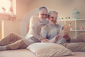 Senior couple enjoying at home and reading book before sleeping