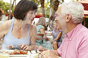 Senior Couple Enjoying Meal In Outdoor Restaurant Together