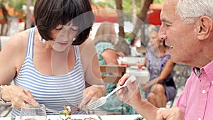 Senior Couple Enjoying Meal In Outdoor Restaurant Together