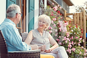 Senior couple enjoying their coffee on porch in front of their house