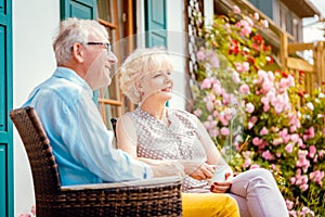 Senior couple enjoying their coffee on porch in front of their house