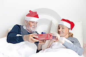 Senior couple exchange gift in their bed during the christmas