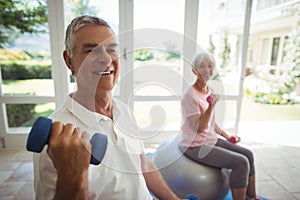 Senior couple exercising with dumbbells on exercise ball