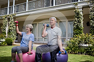 Senior couple exercising with dumbbells on fitness ball